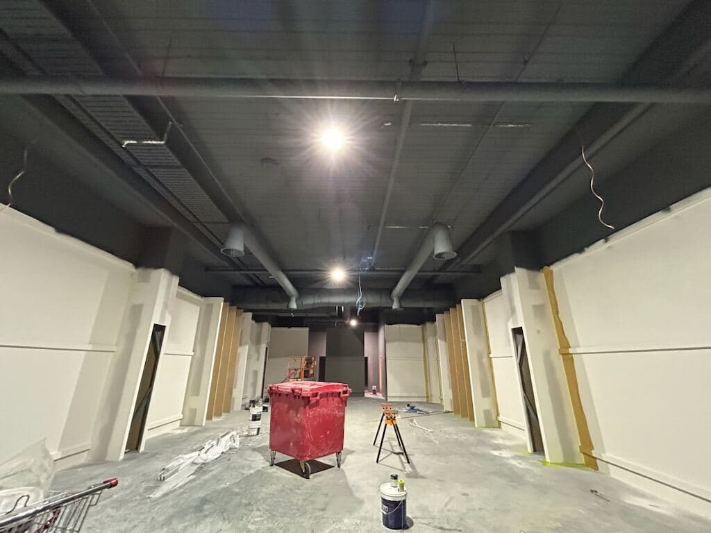General Pants Co. interior mid fit-out — black sprayed ceiling and ductwork with prepped white walls by VD Painting