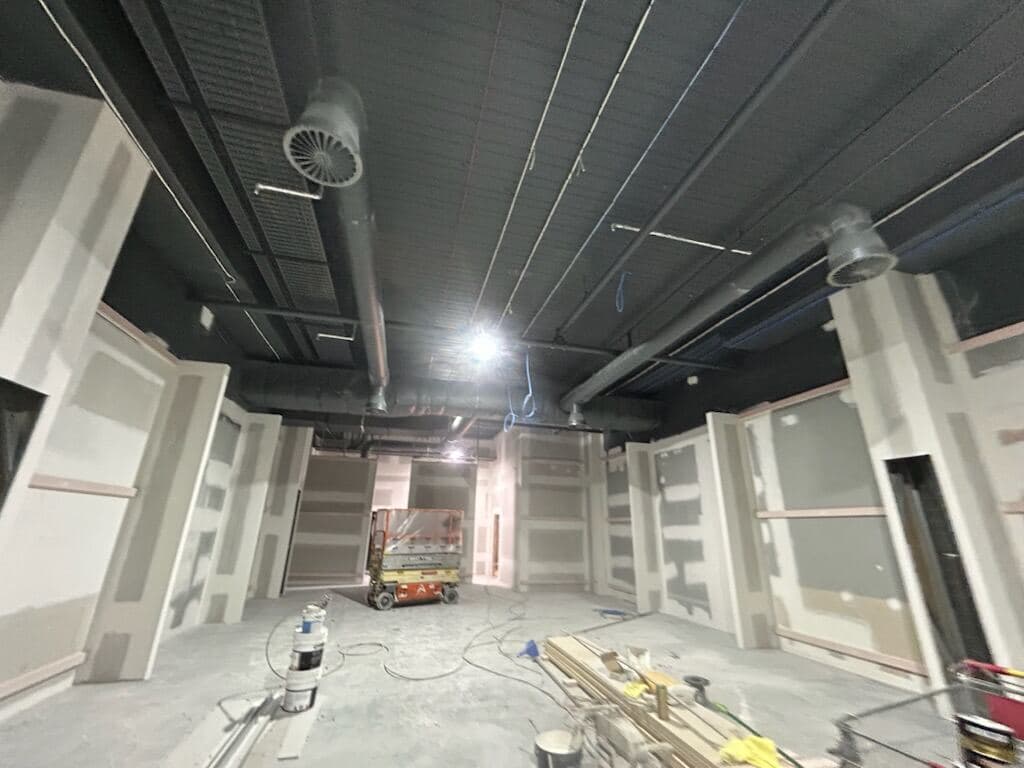 Prep stage at General Pants Co. — scissor lift in place with sprayed black ceiling and patched walls ready for top coats by VD Painting