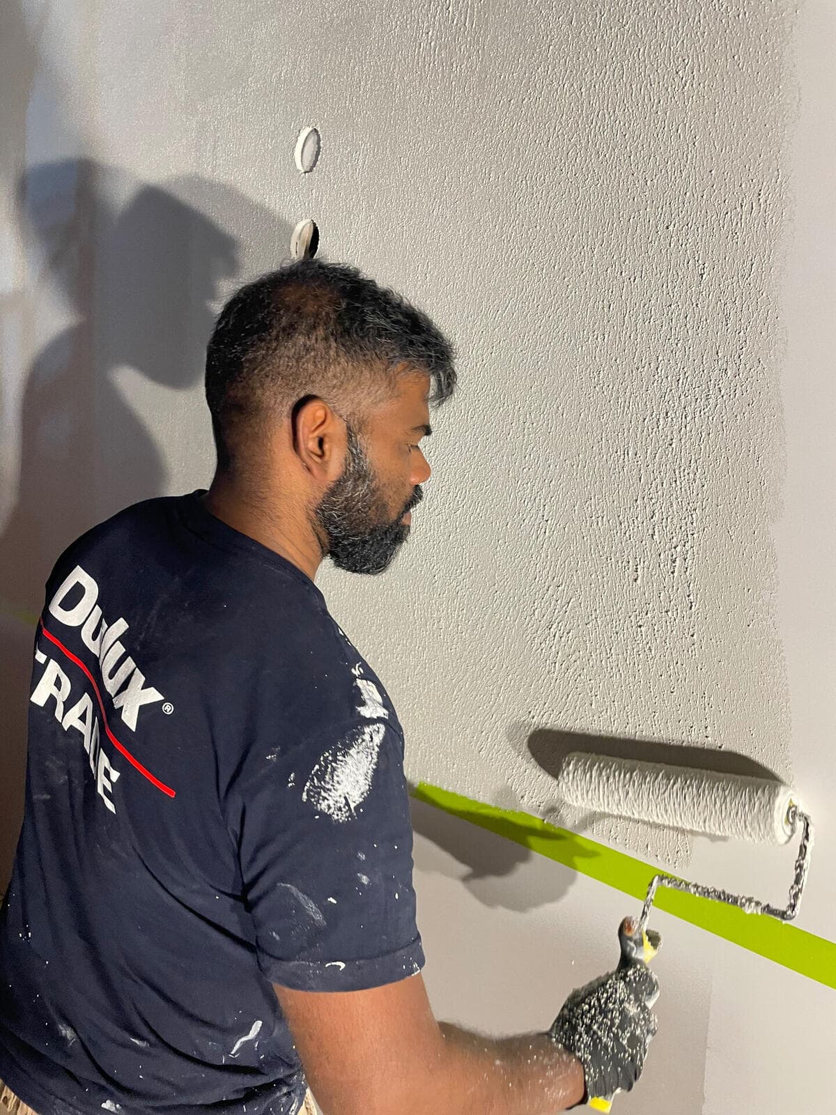 VD Painting crew member rolling Dulux AcraTex textured paint onto the YOMG tester wall (work in progress)