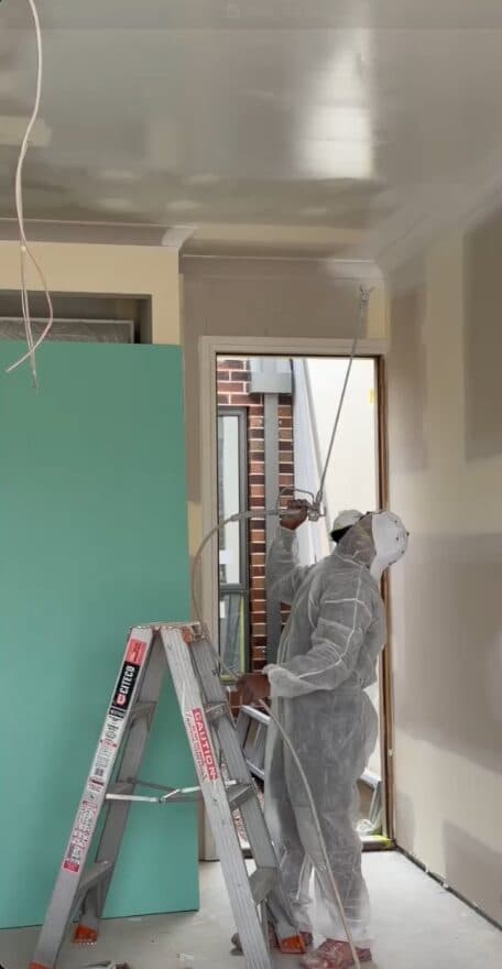 Before — VD Painting crew in protective suits spray painting the ceiling of a VIC home interior (work in progress)