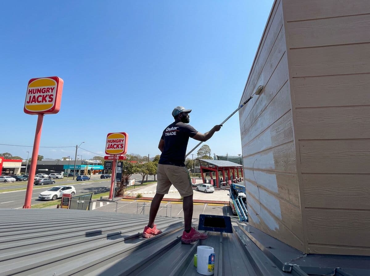 VD Painting crew member rolling fresh paint onto the exterior wall of Hungry Jack's